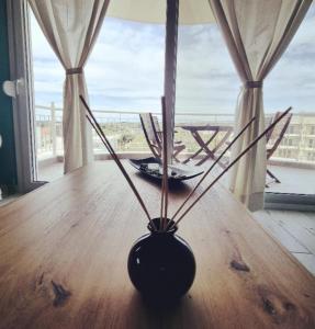 a black vase sitting on a wooden table with a window at Tararas apartments in Néa Michanióna