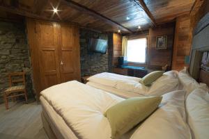 a bedroom with three beds and a television in it at Café Quinson Relais de Charme in Morgex