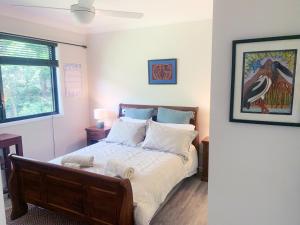 a bedroom with a bed with white sheets and a window at Quiet Private Nimbin Townhouse in Nimbin
