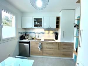 a kitchen with white cabinets and a sink at CAP SUD 83 APPART VUE MER 200m plages in Hyères