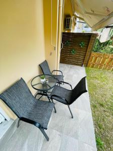 d'une terrasse avec 3 chaises et une table en verre. dans l'établissement Zoi Studios, à Kastrópoulon