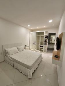 ein weißes Schlafzimmer mit einem Bett und einem Spiegel in der Unterkunft Casa de praia mangaratiba in Mangaratiba
