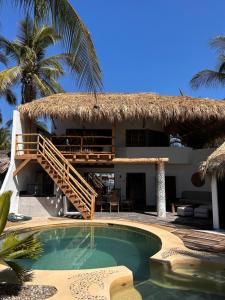 ein Resort mit Swimmingpool und einem strohgedeckten Gebäude in der Unterkunft Villa Bamboo in Coyuca