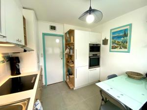 a kitchen with white cabinets and a table in it at CAP SUD 83 APPART VUE MER 200m plages in Hyères