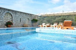 une grande piscine avec des chaises et un patio dans l'établissement Villa Alkmini, à Agnítsini