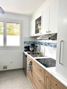 cocina con armarios blancos, fregadero y ventana en CAP SUD 83 APPART VUE MER 200m plages, en Hyères