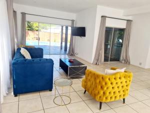 sala de estar con 2 sillas azules y mesa en AveBulela Penthouse en Richards Bay