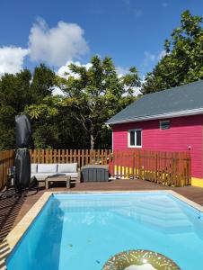 - une piscine en face d'une maison rouge dans l'établissement Kaz Kalina - Gîtes avec piscine partagée, à Bouillante
