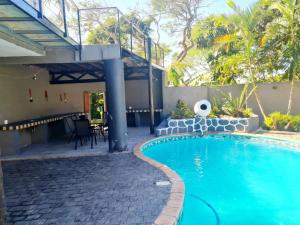 a swimming pool with a patio and a house at AveBulela Penthouse in Richards Bay