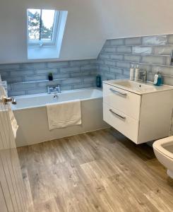a bathroom with a bath tub and a sink at Luxury 2 bed home in Stagsden