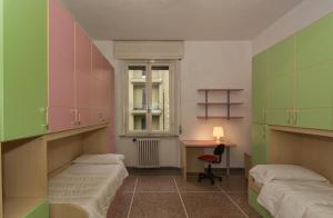 een kamer met 2 bedden, een bureau en een raam bij Holiday Pisa Gare 2 in Pisa