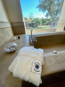 a bathroom with a bath tub with a towel at Villa Sahar Palmeraie avec piscine chauffée ! in Marrakech