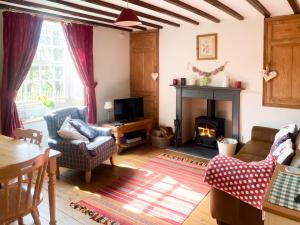 a living room with a fireplace and a table at Beckside Cottage in Fryup