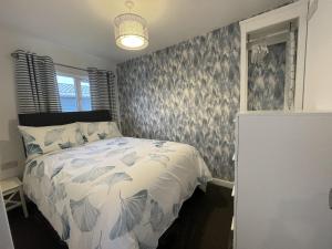 Schlafzimmer mit einem Bett mit einer blauen und weißen Bettdecke in der Unterkunft Isla's Haven Holiday Chalet in Bridlington