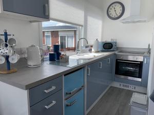 a kitchen with blue cabinets and a clock on the wall at Isla's Haven Holiday Chalet in Bridlington