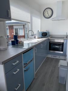 eine Küche mit blauen Schränken und einer Uhr an der Wand in der Unterkunft Isla's Haven Holiday Chalet in Bridlington
