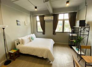 a bedroom with a white bed and two windows at Bangpho Story in Bangkok