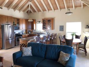 a living room with a blue couch and a kitchen at COCONUT BREEZE VILLA: MESMERIZING VIEWS, COOLING TRADEWINDS in Coral Bay