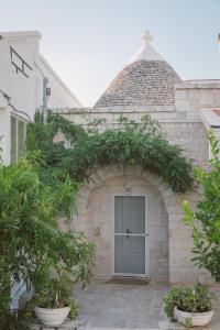 ein Steingebäude mit einer grauen Tür und Pflanzen in der Unterkunft Trulli Harmonia con piscina - Alberobello in Alberobello