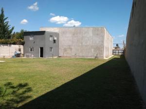 Cabaña piscina parque total privacidad Roldán في رولدان: مبنى خرساني كبير مع ساحة عشب