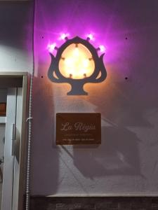 ein Schild an einer Wand mit lila Lichtern in der Unterkunft La Règia in Palagianello