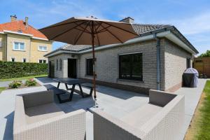 a patio with a table and two chairs and an umbrella at Casa Dunas in Middelkerke