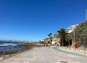 una acera junto a la playa con gente caminando en ella en Quiet Studio with garden 8 Min from Beach, en Estoril