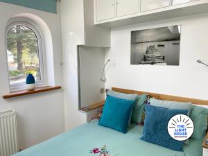 a bedroom with a bed with blue pillows and a window at Welcome to The Light House a tranquil city retreat. in Southampton