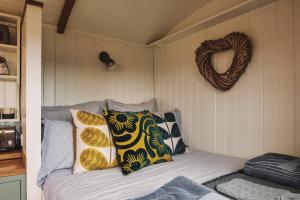 een slaapkamer met een bed met kussens en een krans bij Luxury Shepherd's Hut on Flower Farm with Outdoor Bath in Mid Cornwall in Truro
