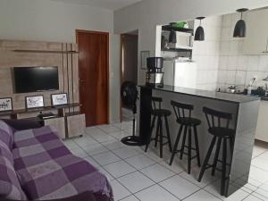 a kitchen with a counter and bar with stools at Apto com estacionamento, piscina e churrasqueira in Bragança Paulista