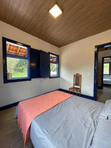 a bedroom with a bed and a chair and two windows at Fazenda do Quartel in Manhumirim