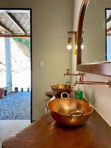 ein Badezimmer mit zwei Kupferwaschbecken auf einer Holztheke in der Unterkunft Fazenda do Quartel in Manhumirim