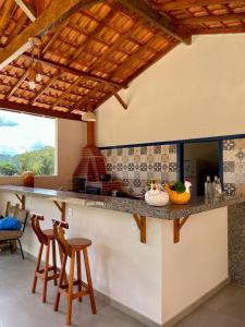 a kitchen with a counter and stools in a room at Fazenda do Quartel in Manhumirim