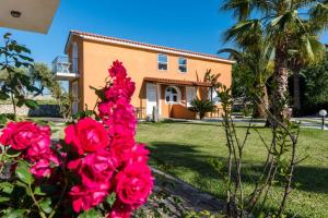 a house with pink roses in front of it at Βessie's Village in Kefallonia
