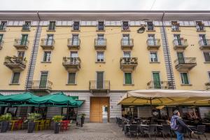 米兰tHE Orange Attic - Navigli Area的一栋黄色的建筑，前面摆着桌椅