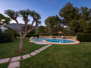a swimming pool in a yard with a tree at HOUSE IN PRIVATE URBANIZATION in Beniarbeig
