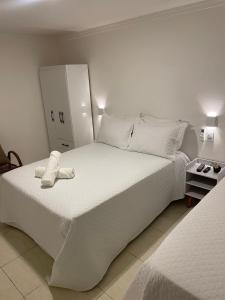 een slaapkamer met een groot wit bed en een kast bij Caroá Piranhas Suítes in Piranhas