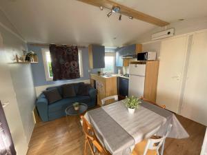 a small kitchen and living room with a table and a couch at Le rêve bleu in Biville-sur-Mer