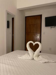 a pair of swans forming a heart on a bed at Caroá Piranhas Suítes in Piranhas