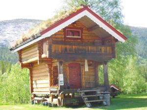 uma pequena cabana de madeira com uma porta vermelha em Lie Hytteutleige -Gjestegård - Thor Fine Art 3 hytte enheter em Åmdals Verk