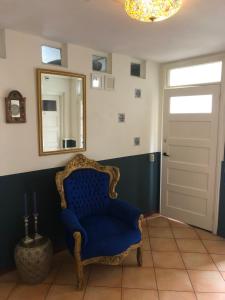 einen blauen Stuhl in einem Zimmer mit Spiegel in der Unterkunft De Witte Handt in Midsland