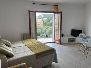 a bedroom with a bed and a sliding glass door at Apartamentos El Sol in Tossa de Mar