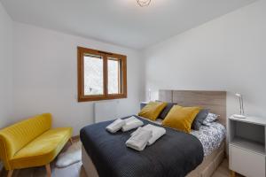 Un dormitorio con una cama y una silla amarilla. en Perle De Savoie - Apt B303 - BO Immobilier - remises sur les forfaits de skis Châtel ou Portes du soleil, en Châtel