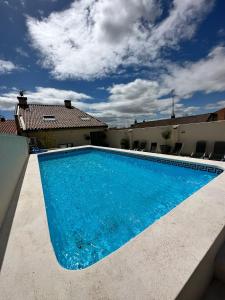 une grande piscine bleue en face d'une maison dans l'établissement Hostal Comfort Suites, à Carrión de los Condes