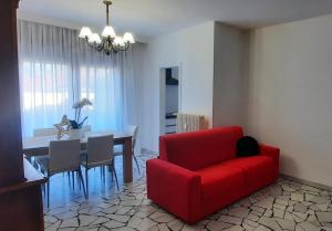 Verdisuite - Trento centro - Parcheggio privato gratuito في ترينتو: غرفة معيشة مع أريكة حمراء وطاولة