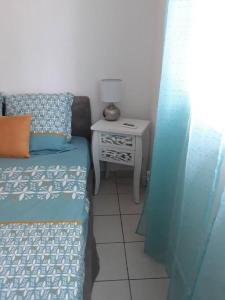 ein Schlafzimmer mit einem Bett und einem Tisch mit einer Lampe in der Unterkunft Studio Colibri Baie-Mahault in Baie-Mahault