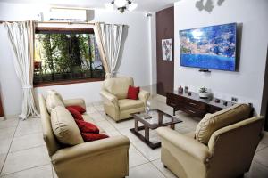 a living room with two couches and a tv at Las Orquídeas Hotel Boutique in Asuncion