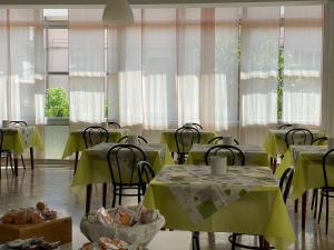 a dining room with tables and chairs and windows at Hotel Apis in Rimini