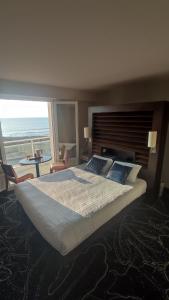 a bedroom with a large bed with a view of the ocean at Hotel La Corniche in Saint-Hilaire-de-Riez