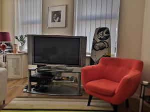 uma sala de estar com uma televisão e uma cadeira vermelha em Lovely Master Bedroom with King Size Bed em Liverpool